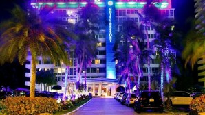 A hotel with a prominent vertical sign, multiple floors, and a well-lit entrance. - Oceanfront Studio w/balcony & Private Beach - Walk to shops & Dining (Fort Lauderdale)