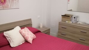 Una camera da letto con un letto, una cassettiera, uno specchio e una parete con un poster.