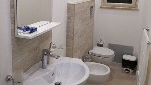 Un bagno compatto con lavandino bianco, uno specchio, un WC e un bidet.