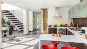 A modern kitchen with a dining area, a staircase, and a view of the outdoors. - Casa Di Verde Villa (Platanias)