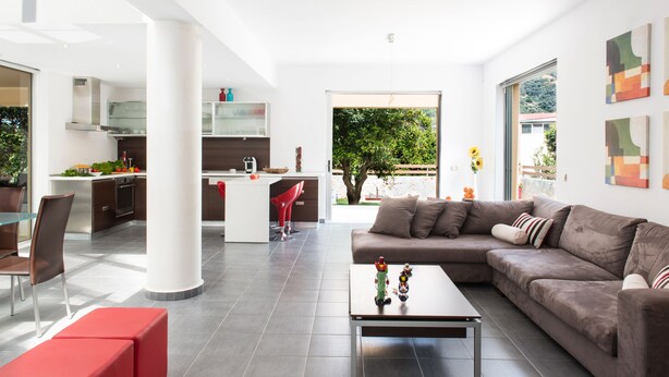 A modern living space with a kitchen, dining area, and a large window offering a view of greenery. - Casa Di Verde Villa (Platanias)