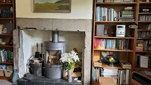 A cozy living room with a fireplace, bookshelves, and a painting on the wall. - Victorian cottage, large gardens, near river, Hadrian's Wall & Allendale (Allendale)
