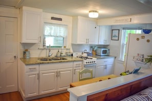 Kitchen equipped with a stove, microwave, sink, and refrigerator.