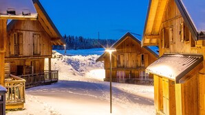 A wooden cabin with a porch and a snow-covered ground. - Appart proche de la navette aux pistes (Les Déserts)
