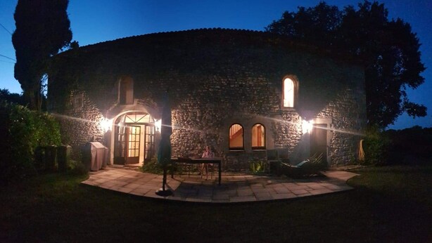 A stone building with a circular patio, a covered outdoor seating area, and a well-lit entrance. - Private pool and secluded garden.  Sleeps 4 adults  maximum + 4 children. (Édon)