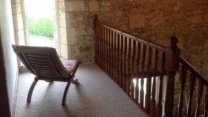 A stone-walled corridor with a wooden chair and a wooden railing. - Private pool and secluded garden.  Sleeps 4 adults  maximum + 4 children. (Édon)