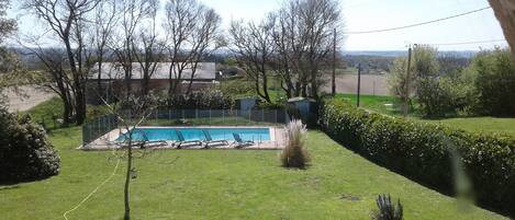 A backyard with a swimming pool, surrounded by a fence and trees.