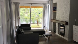 A modern living room with a sofa, a fireplace, and a view of a garden.