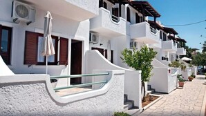A row of white buildings with balconies, air conditioning units, and potted plants. - New Aurora By Checkin (Ierapetra)