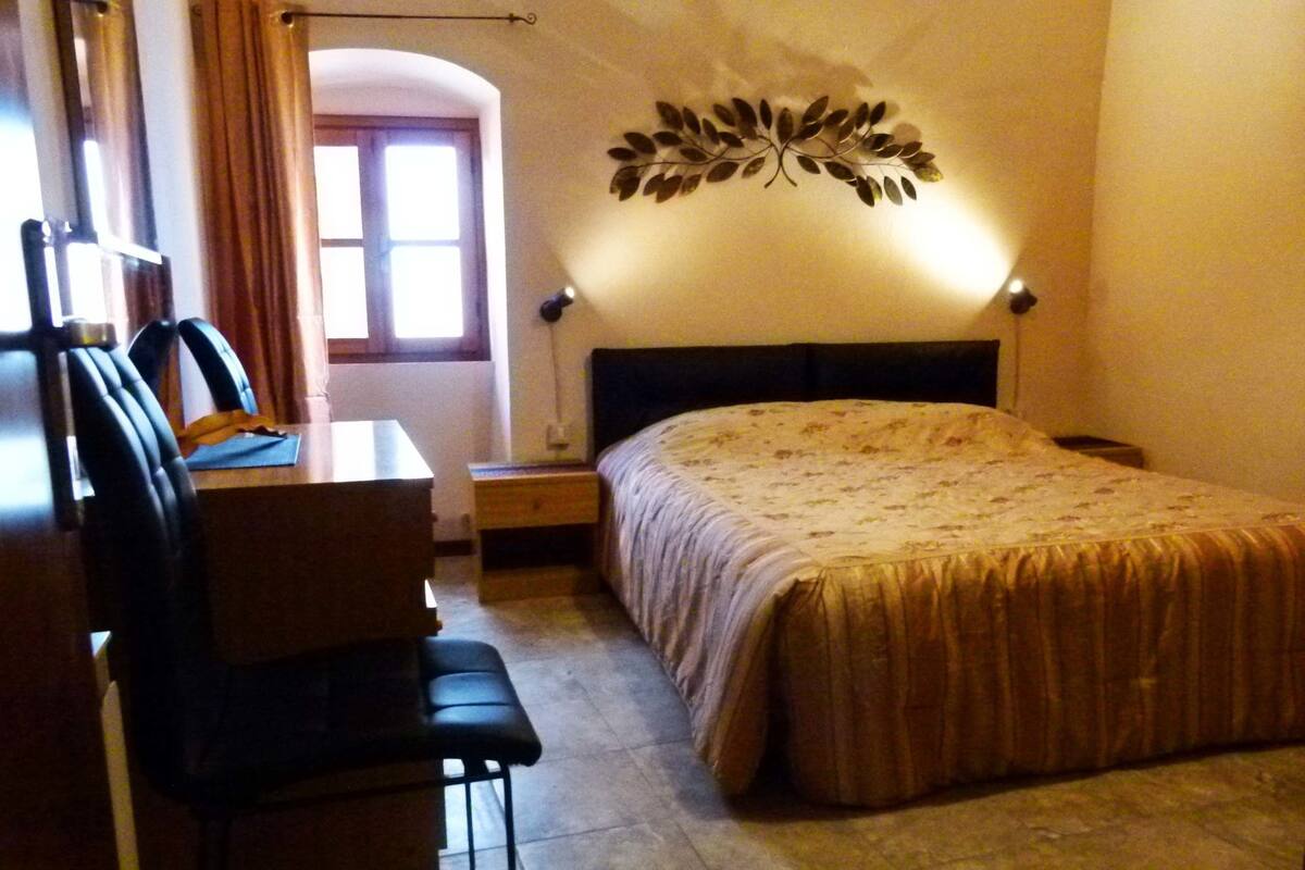 Hotellihuone, jossa on sänky, työpöytä, tuoli ja koristeellinen seinäelementti.