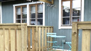 Une terrasse en bois avec une table et des chaises, une clôture en bois et une fenêtre.