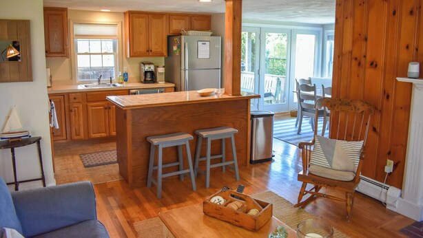 Una cocina amplia con armarios de madera, una isla central con taburetes y vistas a la terraza exterior.