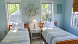 Un dormitorio con dos camas, una rueda de barco y un letrero que dice 'Cottage Rules'.