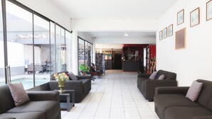 A spacious lobby with a pool view, multiple seating areas, and a reception desk. - Hotel Concorde (Arica)