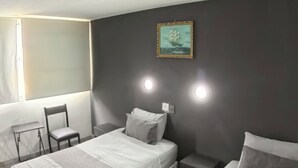 A hotel room with two beds, a chair, a desk, and a wall-mounted picture. - Hotel Concorde (Arica)