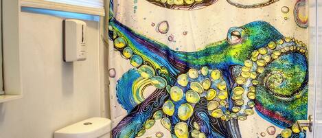 A bathroom with a white toilet, a white sink, and a shower curtain with a colorful octopus design.