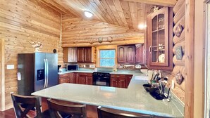 Une cuisine de style rustique, avec un îlot central, des armoires en bois et une fenêtre laissant entrer la lumière naturelle.