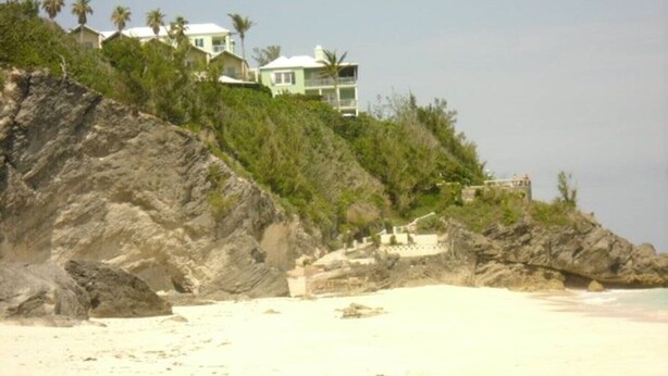 Una propiedad frente a la playa con varias casas sobre un acantilado, con vista al mar.