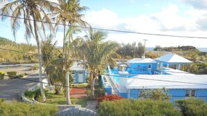 Una propiedad costera con un edificio azul, palmeras y un arco de piedra.