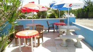 Un patio al aire libre con mesas, sillas, sombrillas y un letrero de Pepsi.