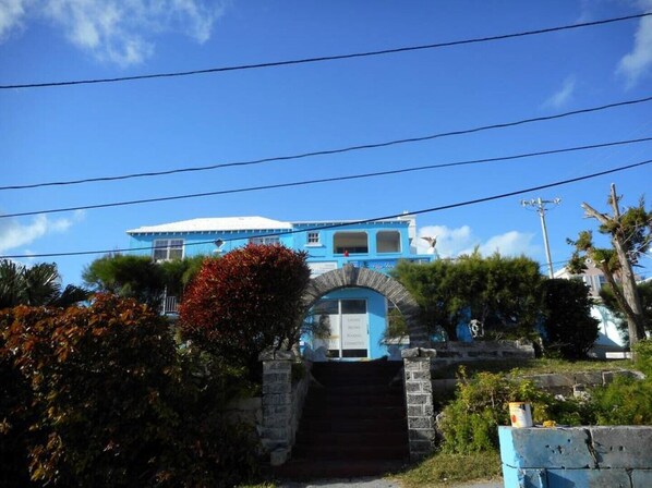 A blue building with a white roof, a stone archway entrance, and a staircase leading up to it. - Blue Horizons Guest House - Studio # 11 (Warwick)