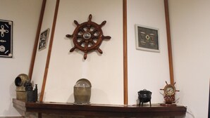 Ein gemütliches Wohnzimmer mit Kamin aus Stein, einem Schiffahrtstisch und maritime Dekorationen.