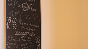 Eine Schiefertafel mit Frühstücks- und Abendessenszeiten, eine Kaffeemaschine und eine Holztresen mit Spiegel und kleiner Schublade.