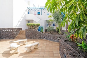 A courtyard with a stone bench, a staircase, and a building with blue accents. - Bluesea Bahia Fanabe and Villas (Adeje)
