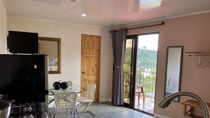 A kitchen with a stove, sink, and a dining area with chairs and a table. - Buena Vista Boquete (Boquete)