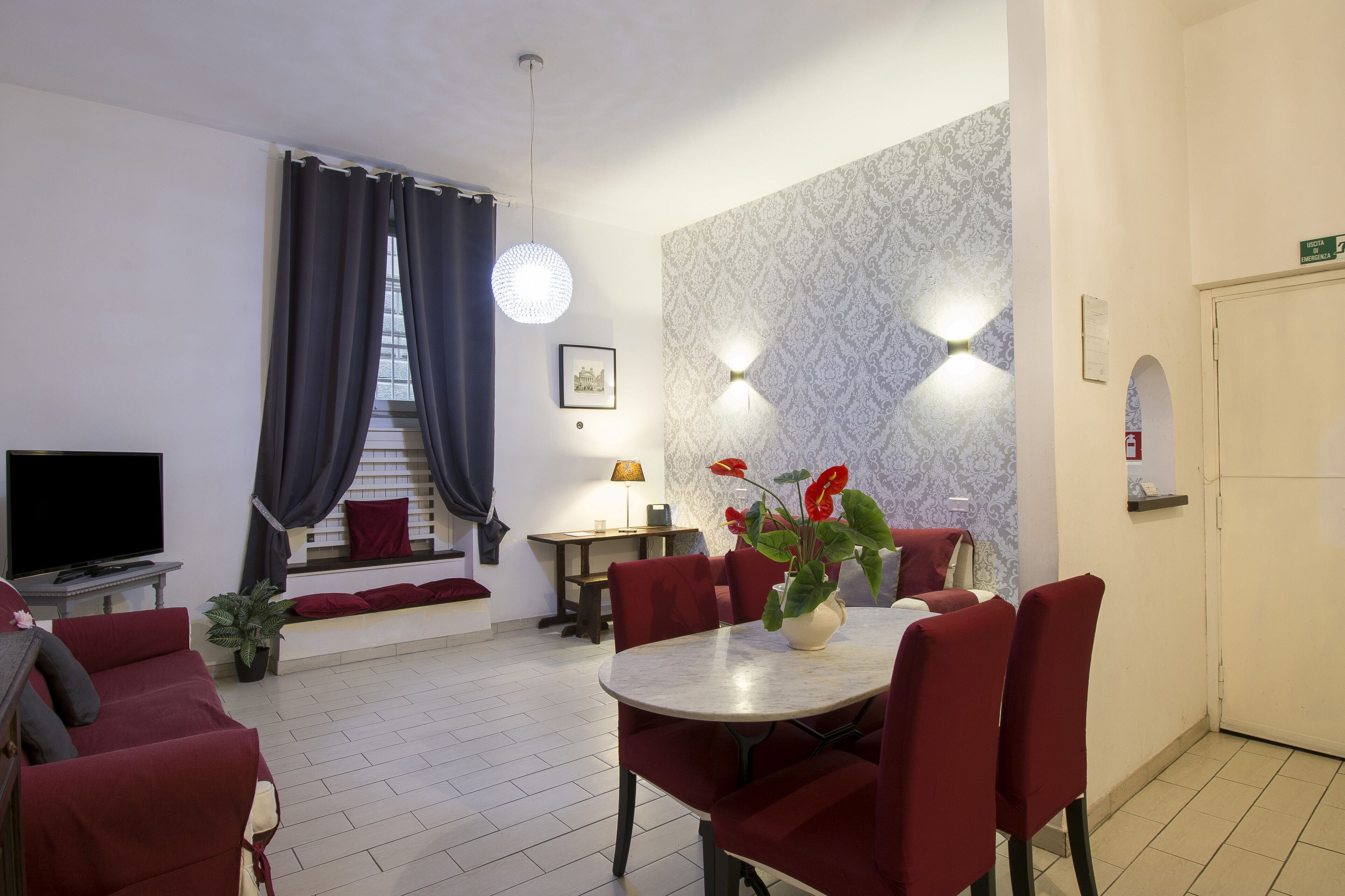 Een hotelkamer met een eethoek, een televisie, een trap en een potplant.