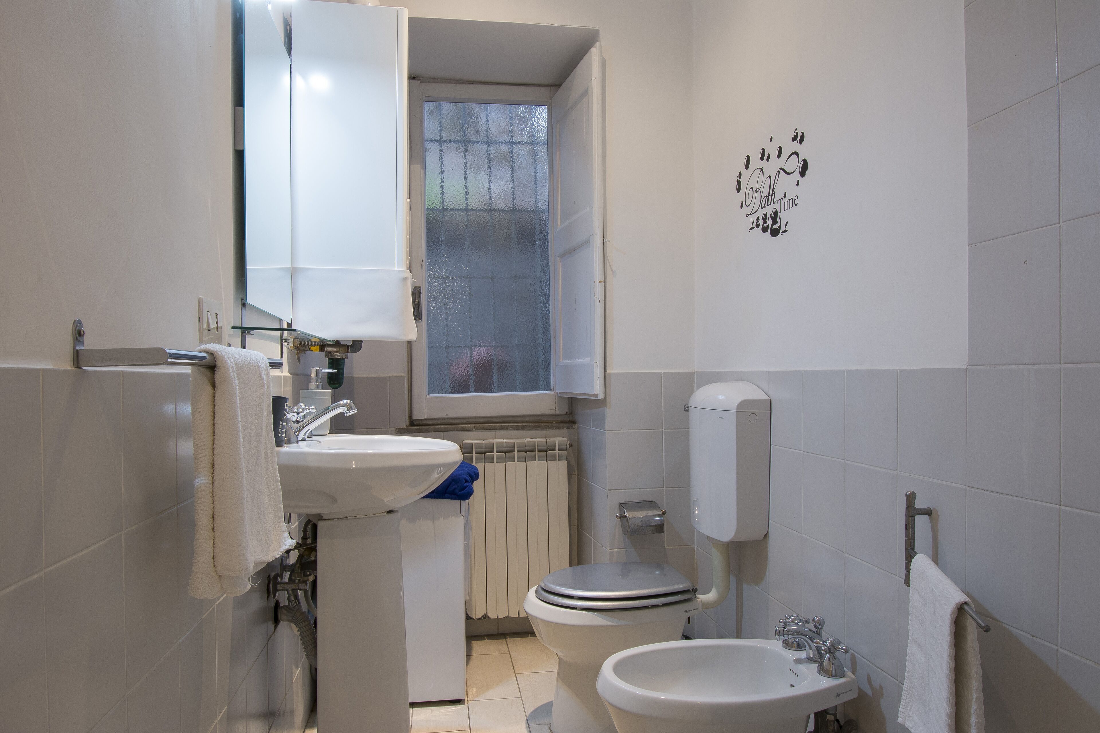 A bathroom with a toilet, sink, and window.