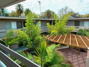 Ein Innenhof mit einer Holz-Pergola, Palmen und einem Backsteinweg.