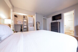 Ein Hotelzimmer mit einem großen Bett, einem Kleiderschrank, einem Fernseher und einem durch eine offene Tür einsehbarer Badezimmer.