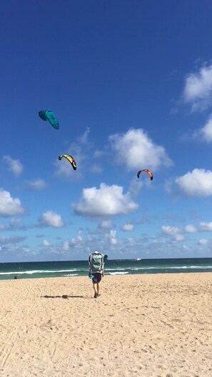 A beach with a person walking towards the ocean, carrying a backpack.