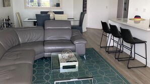 A modern living room with a sectional sofa, a glass coffee table, and a patterned rug. - Beautifully modern just renovated steps away from the Beach. (Miami Beach)