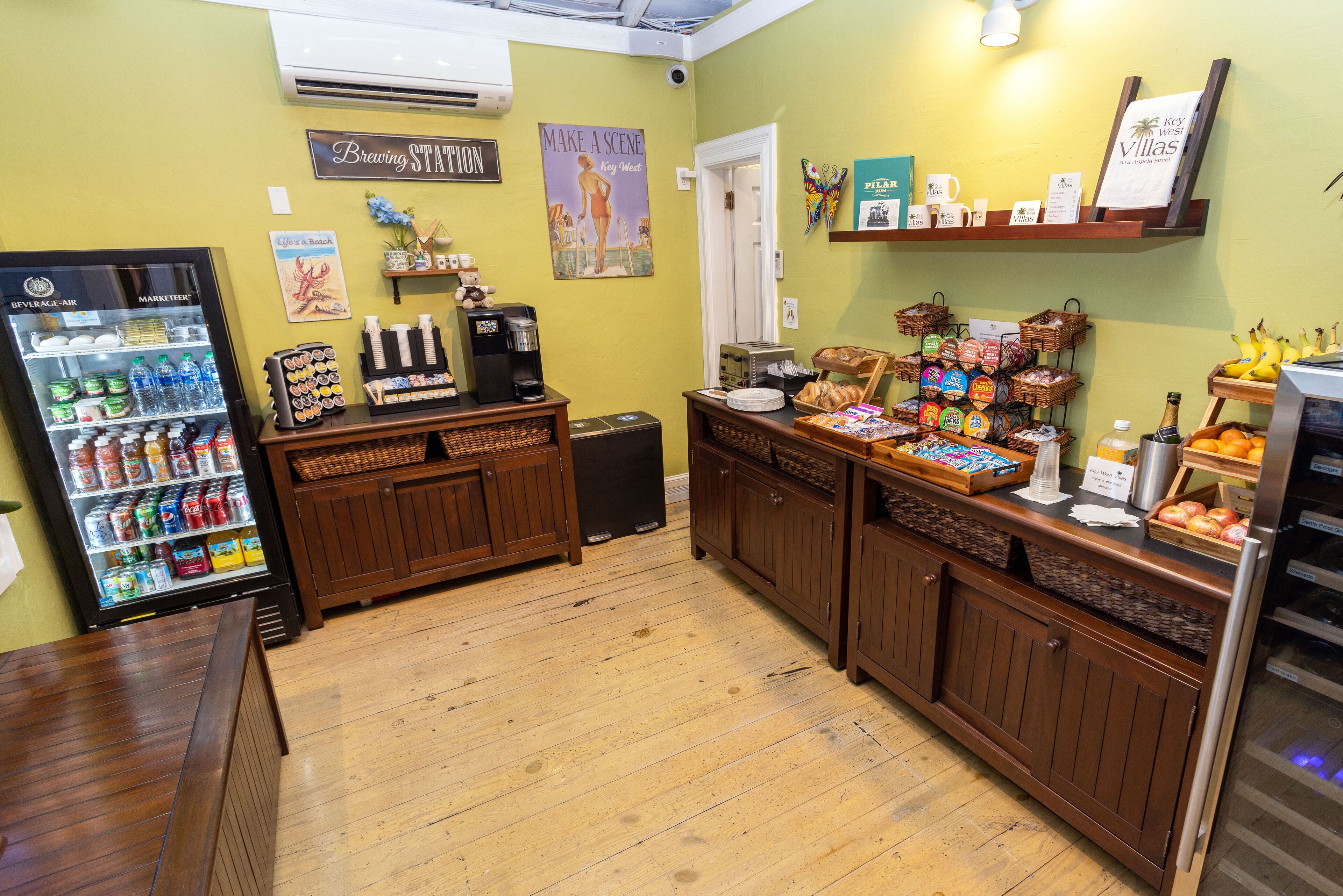 Una cafetería con mostrador de madera, refrigerador para bebidas y diversos productos alimenticios a la vista.
