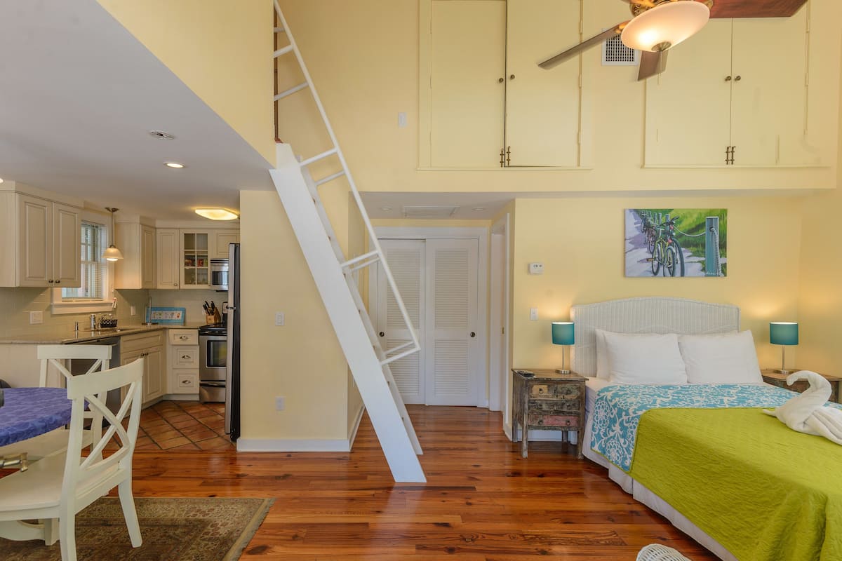 A compact bedroom with a bed, bedside lamps, and a painting on the wall.
