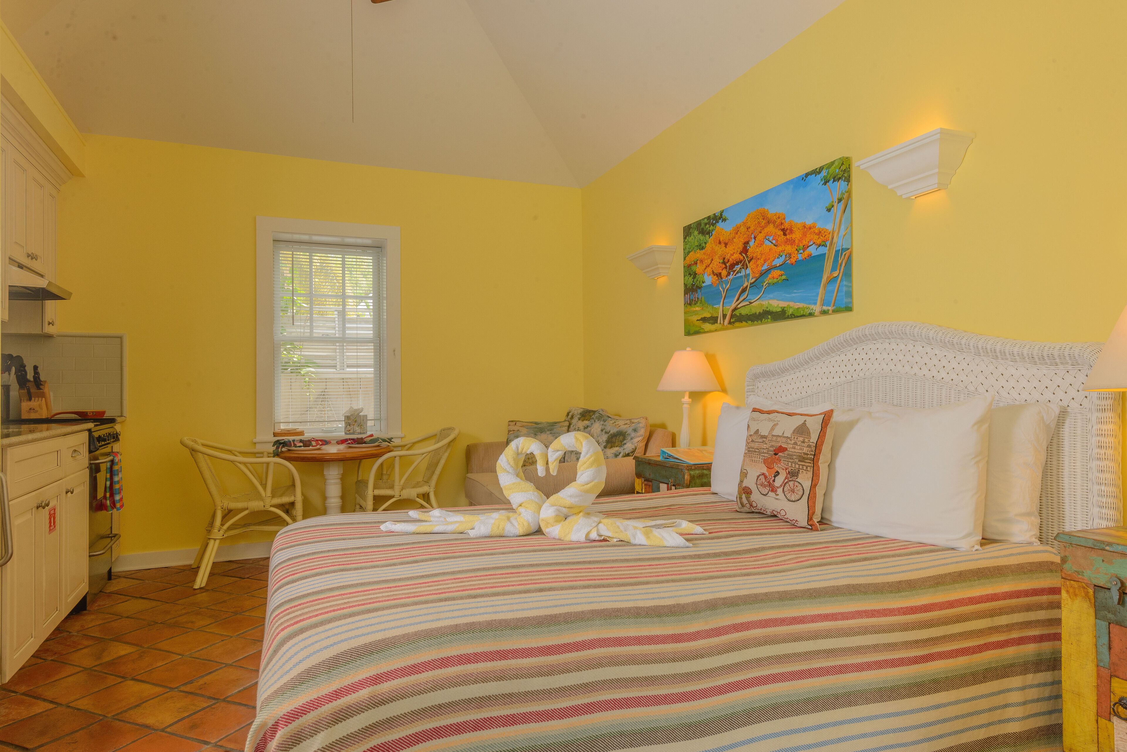 A room with a bed, a dining table, and a kitchen area.