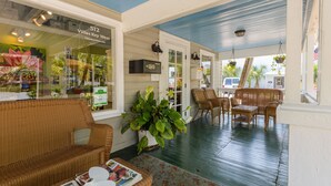 A covered porch with wicker furniture, a large potted plant, and a sign for Villas Key West. - Key West Villas (Key West)