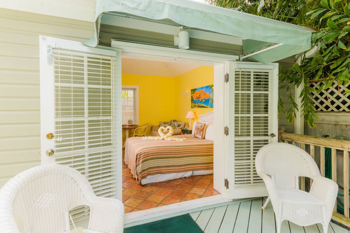 A room with a bed, a chair, and a door leading to another room.