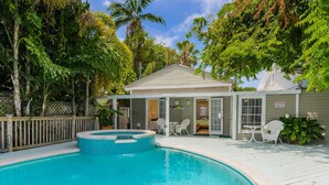 A swimming pool with a hot tub, surrounded by a wooden deck and lush greenery. - Key West Villas (Key West)