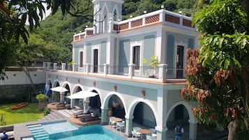 Alberca al aire libre, sombrillas en la alberca y camastros