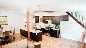A spacious kitchen with dark cabinets, a central island, and a dining area with a sofa and chairs.