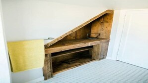 A corner of a room with a wooden bench and a small shelf.