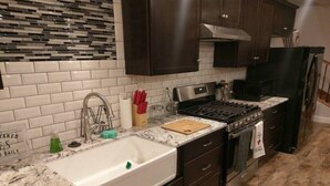 A kitchen with dark cabinets, a white sink, a stove, and a tiled backsplash.