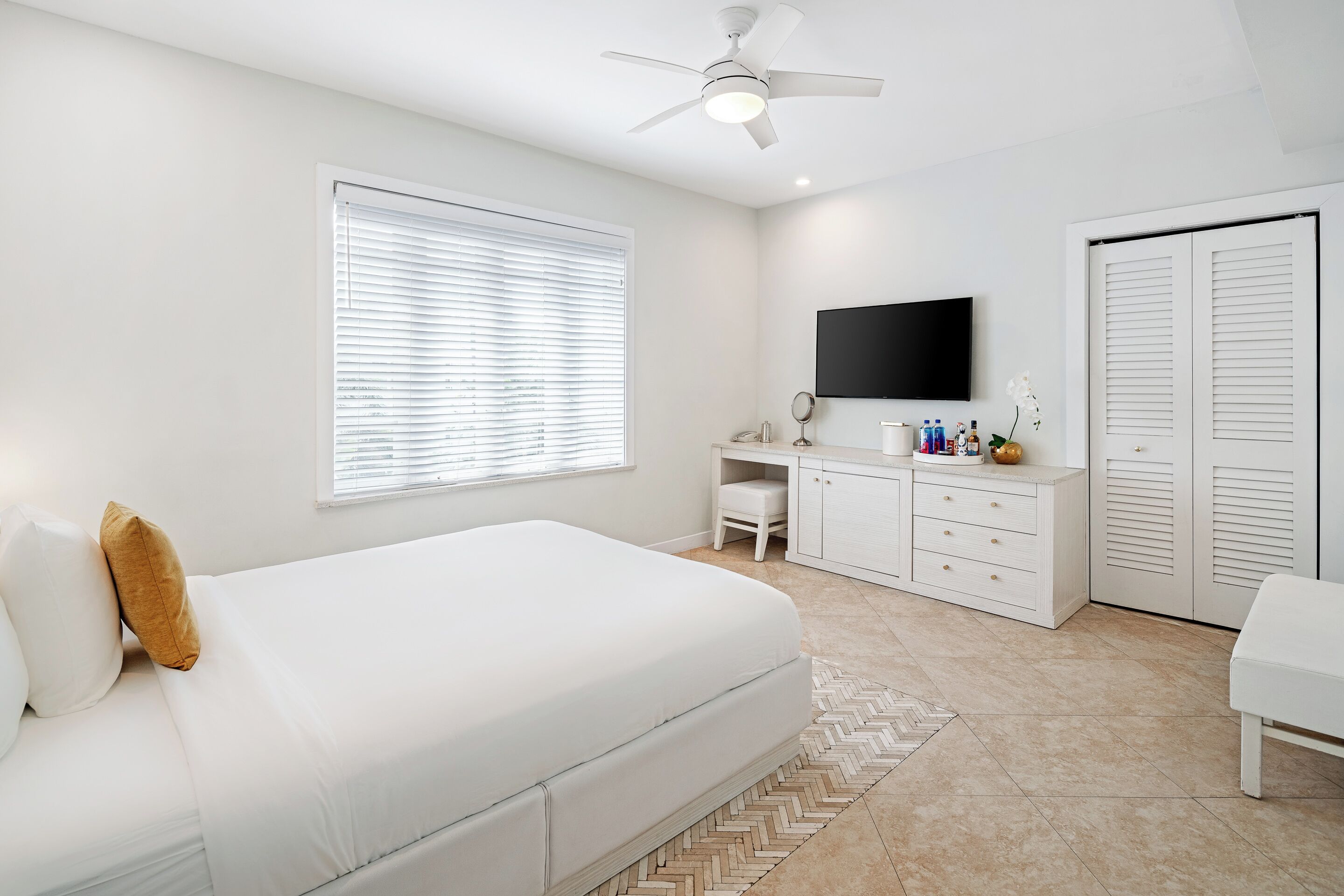 Une chambre à coucher avec un lit, un bureau, une télévision et une armoire.
