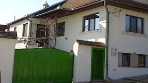 Una casa de dos pisos con techo de tejas, una puerta verde y una valla verde.