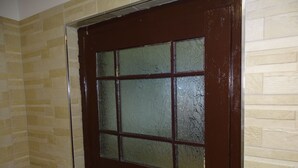 Una puerta marrón oscuro con un ventanal con vidrio satinado, en un cuarto con paredes beige de diseño.