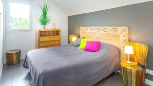 A modern bedroom with a large bed, a wooden headboard, two bedside tables with lamps, a potted plant, and a small wooden cabinet. - Lagoon! Pretty villa at 2 steps from the lagoon of Saline les bains (La Saline-Les-Bains)