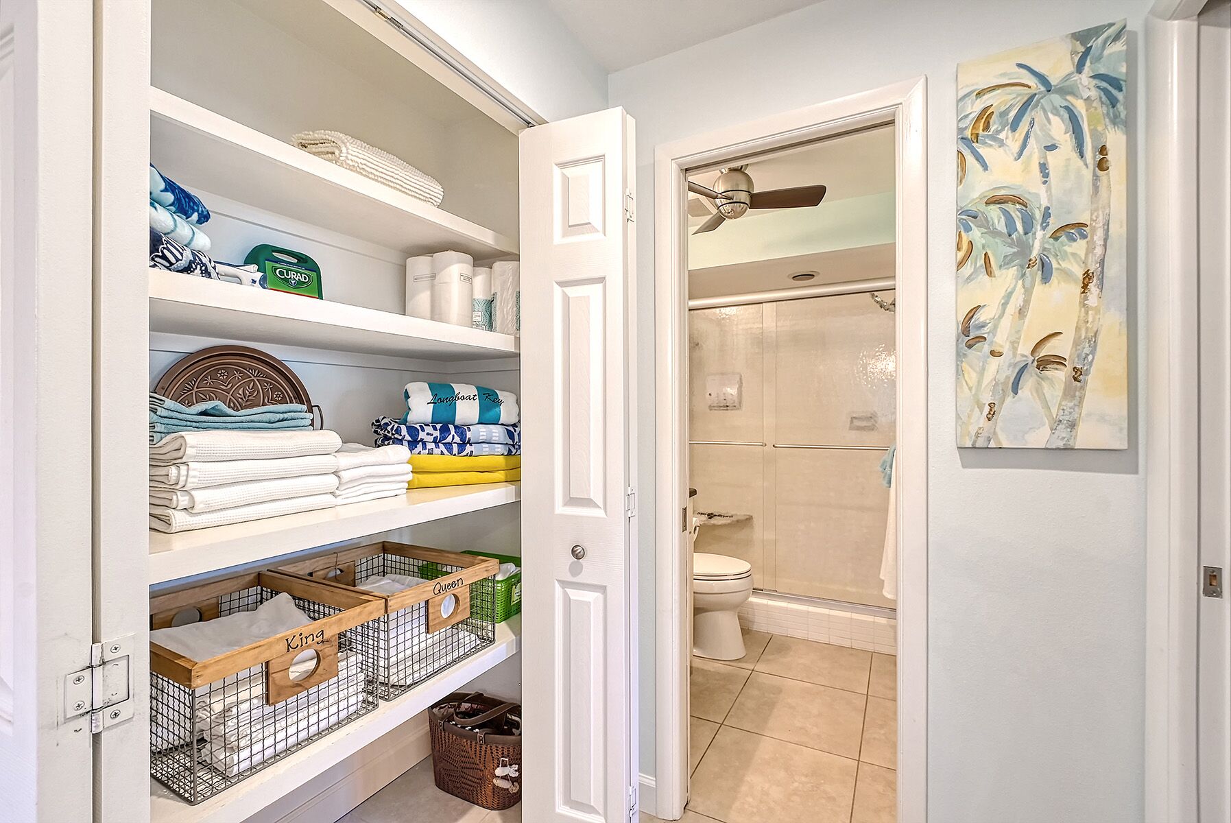A walk-in closet with shelves, a door leading to a bathroom, and a ceiling fan.